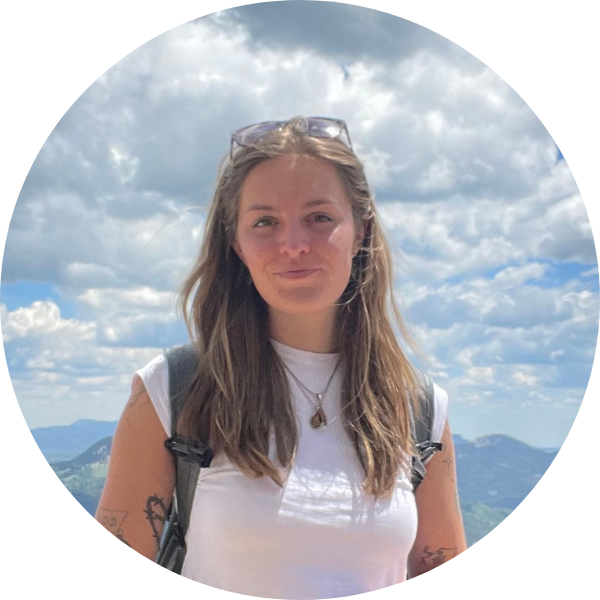 Headshot of Willa standing in a white shirt with blue sky in the background.